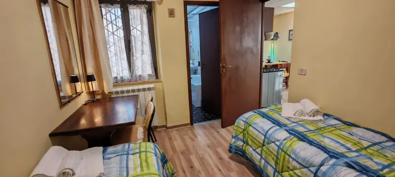 Camera doppia con due letti singoli, scrivania e finestra affacciata sul verde