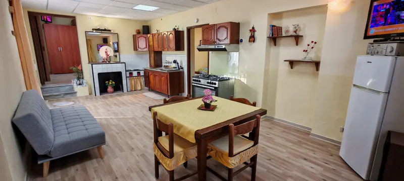 Zona pranzo con tavolo apparecchiato, camino e cucina a gas con forno nel salone della casa Jolie